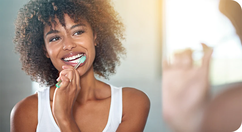 woman brushing her teeth and smiling