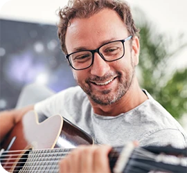 man smiling while playing guitar
